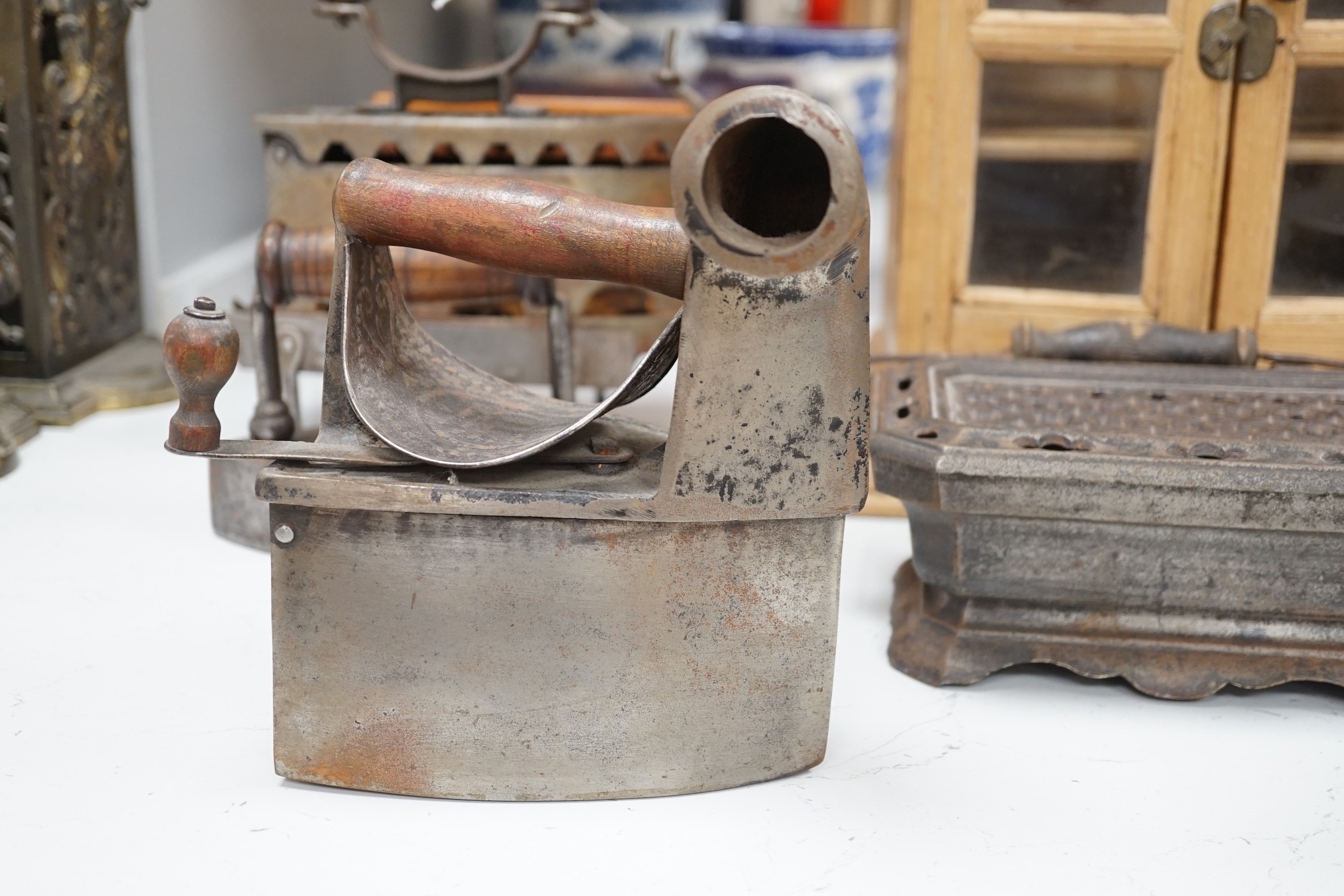 Four French coal/slug irons, three trivets and a stripped pine glazed cabinet, 37cm high